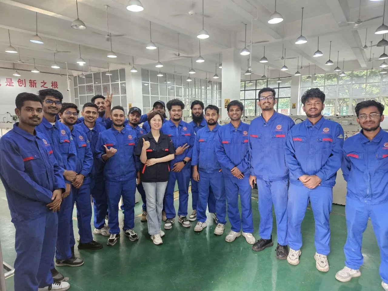 The international students in blue workshop uniforms with their instructor